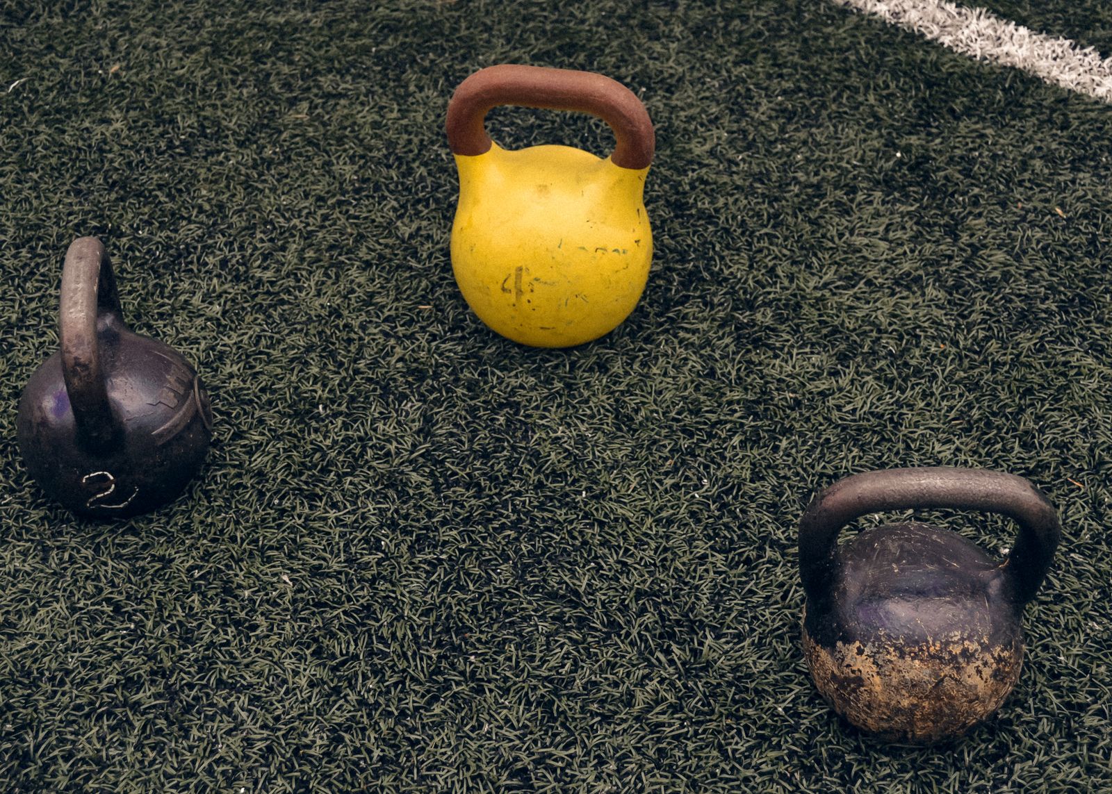 Three kettlebells arranged on grass for an outdoor workout
