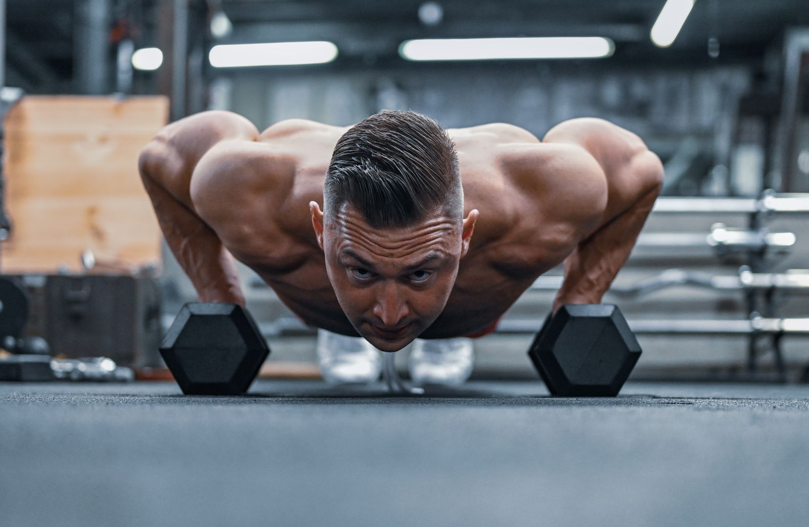 Man performing a controlled push-up using dumbbells as handles
